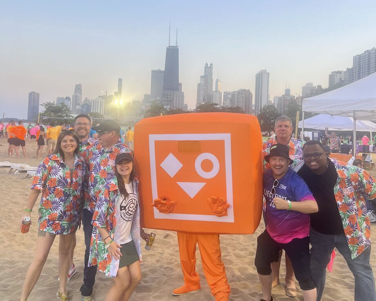 Object First team posing on a beach with the orange mascot